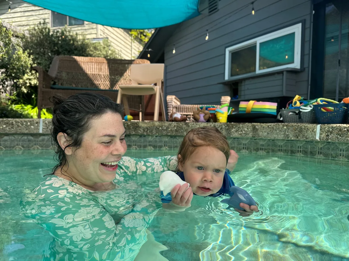 Instructor smiling with a toddler during a Littlest Fish lesson under the shade sail