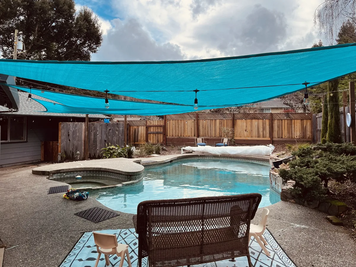 The heated backyard pool at Little Fish Swim School Felton under its blue shade sails