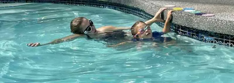 Swim instructor guiding a child in the warm heated pool