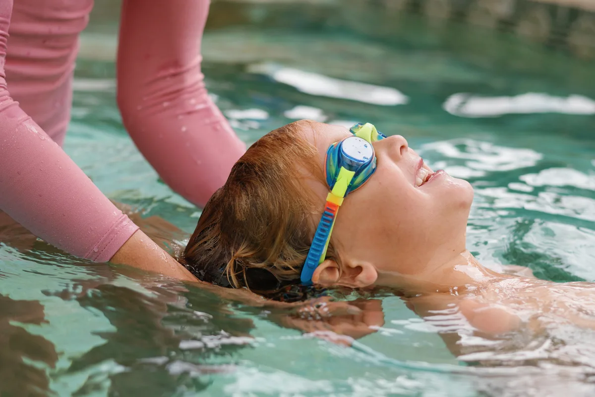 Instructor supporting a young swimmer doing a back float