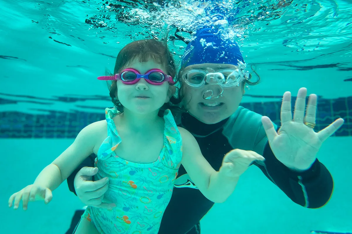 Instructor and student underwater together, both wearing goggles