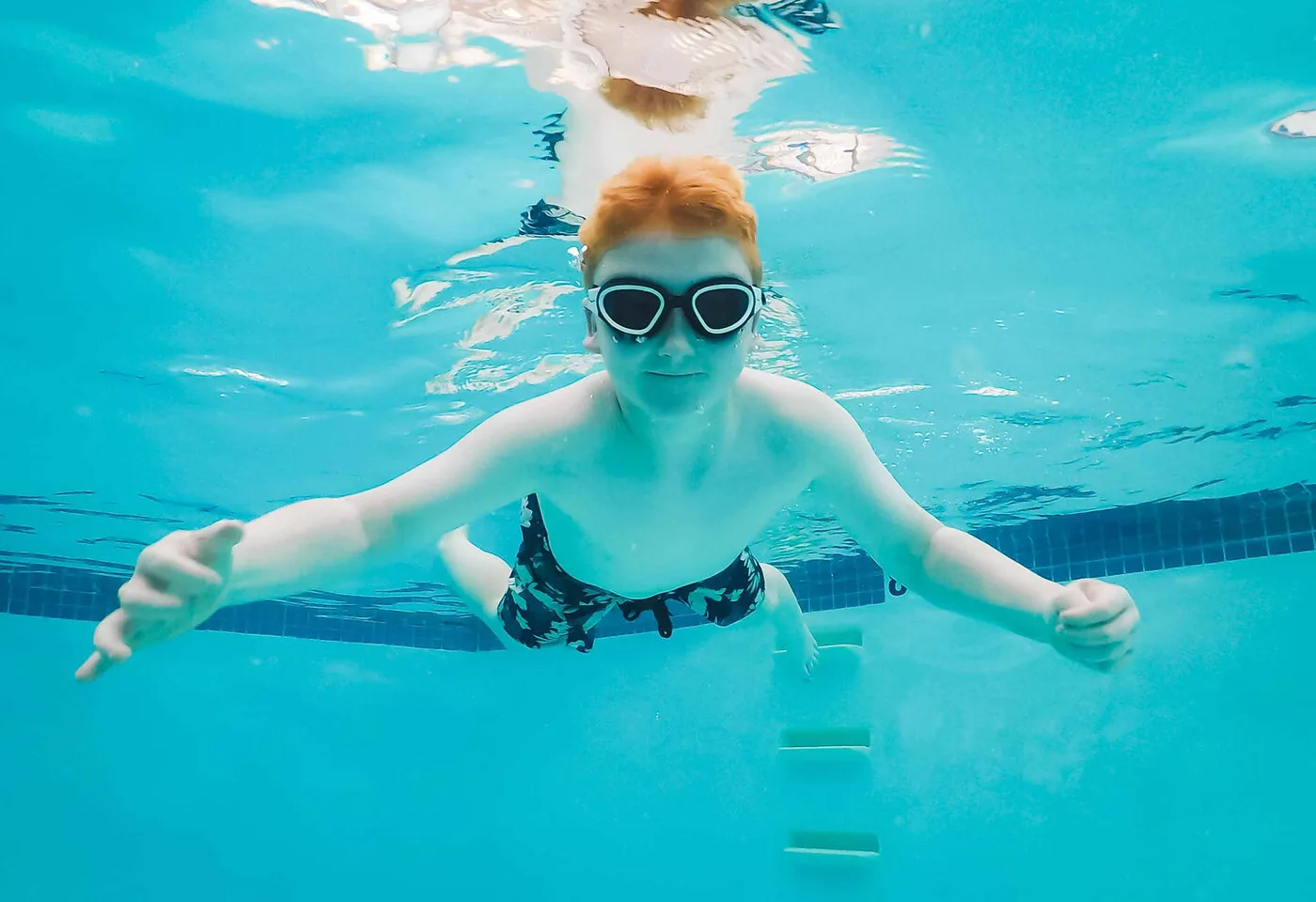 Young swimmer gliding underwater with goggles at Little Fish Swim School