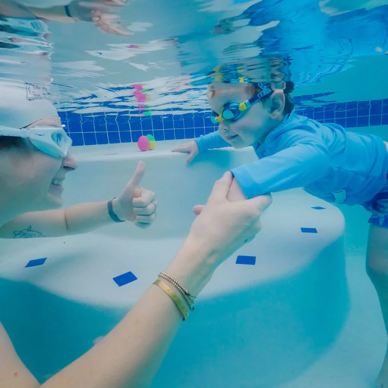 Instructor giving a thumbs-up to a young swimmer in the pool